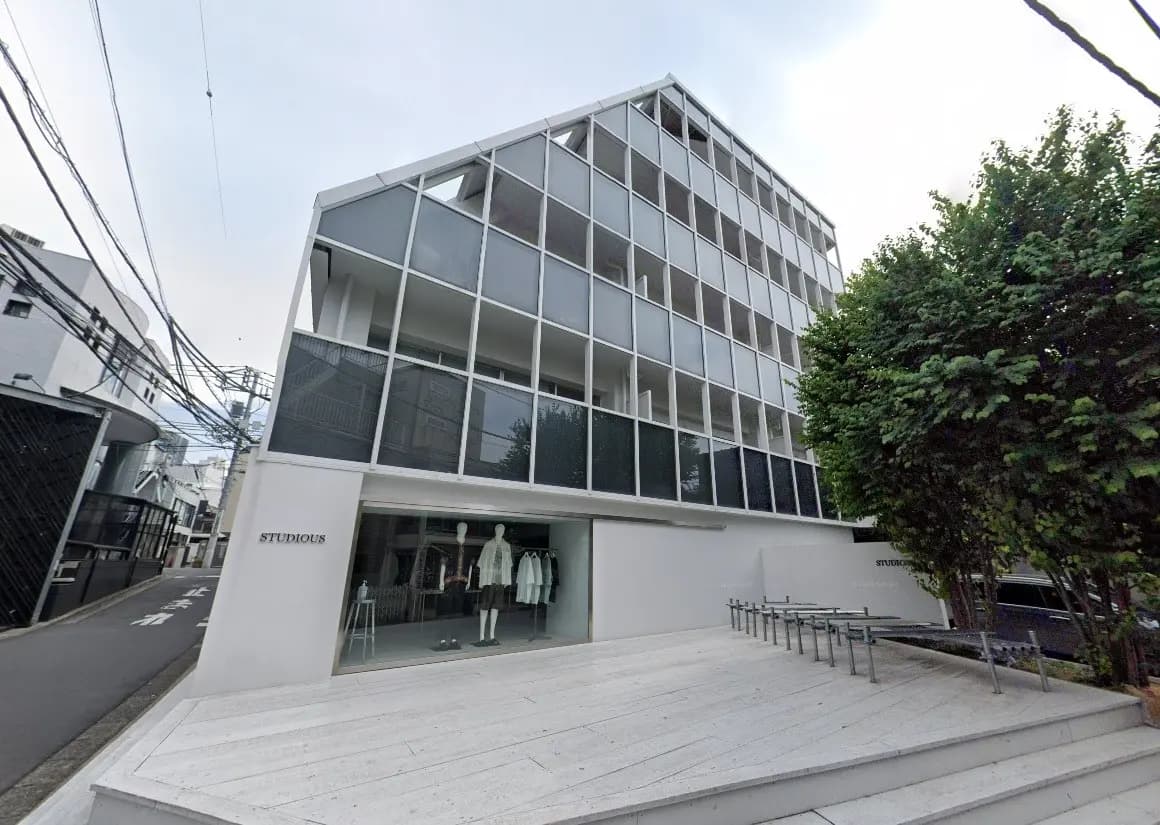 現代的なデザインのSTUDIOUSブランドのファッションストアの外観、白い壁とガラス張り、歩道沿いに位置する