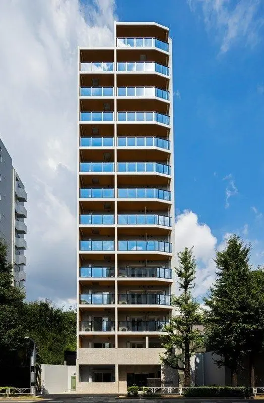 都市の青空に映えるモダンな多階建てのアパートビル、ガラスのバルコニーが特徴