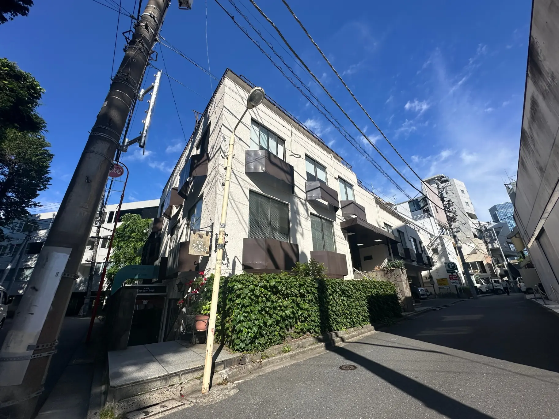 晴れた日の街角、ビルと住宅が立ち並ぶ景色、電線と青空