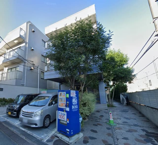 現代的な外観のオフィスビル、前に自動販売機と駐車している車、都市の景観