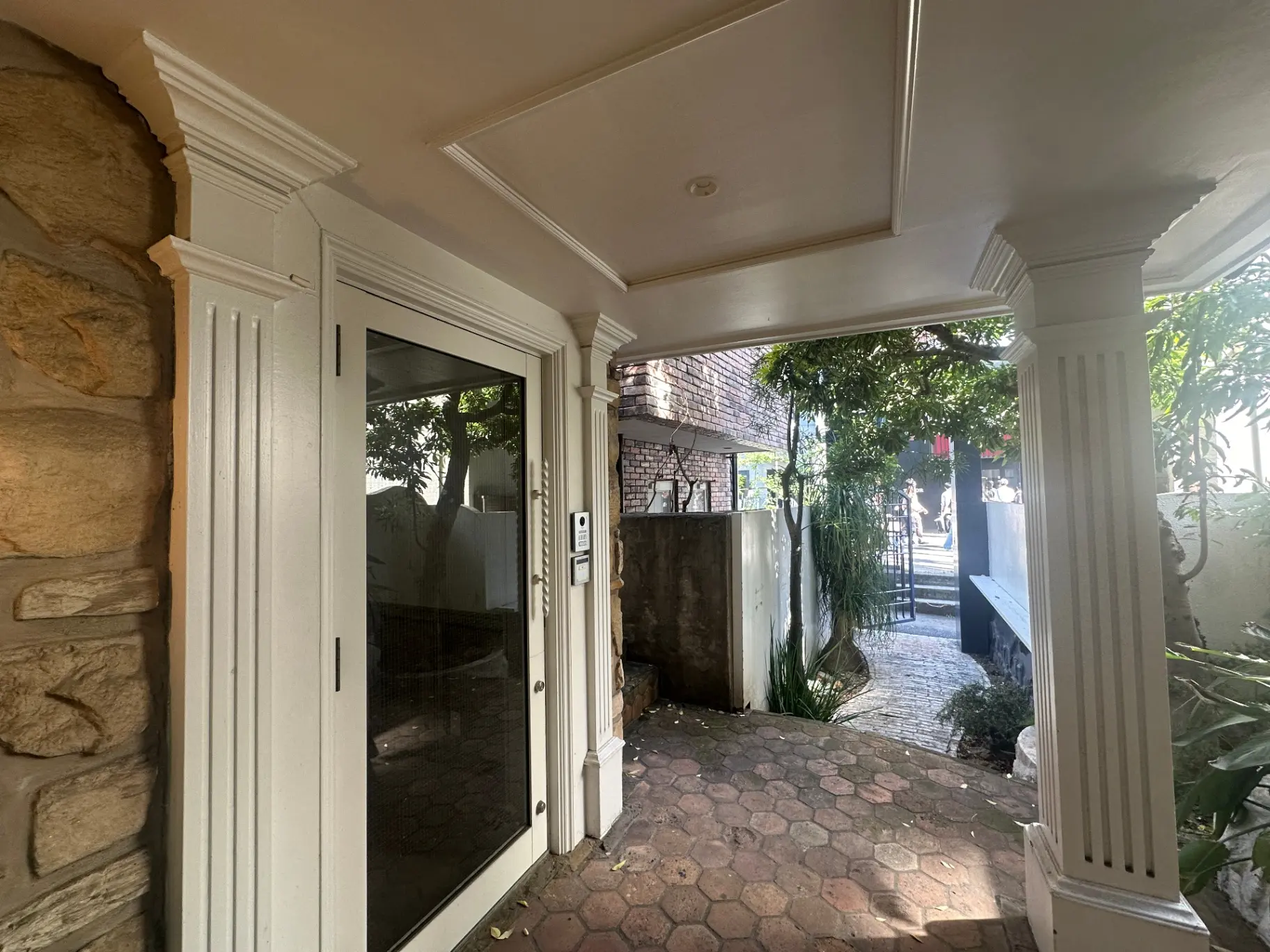 エントランスのアーチ型ドアと石造りの壁、中庭にはガーデンテーブルが見える外観