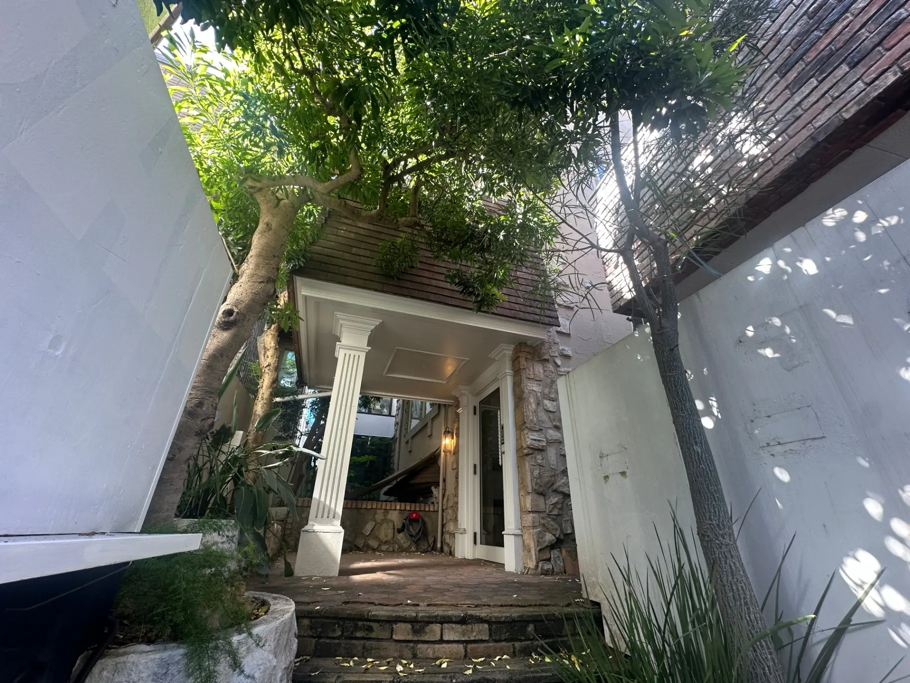自然に囲まれた門戸と石造りの階段、木々の緑が鮮やかな住宅のエントランス