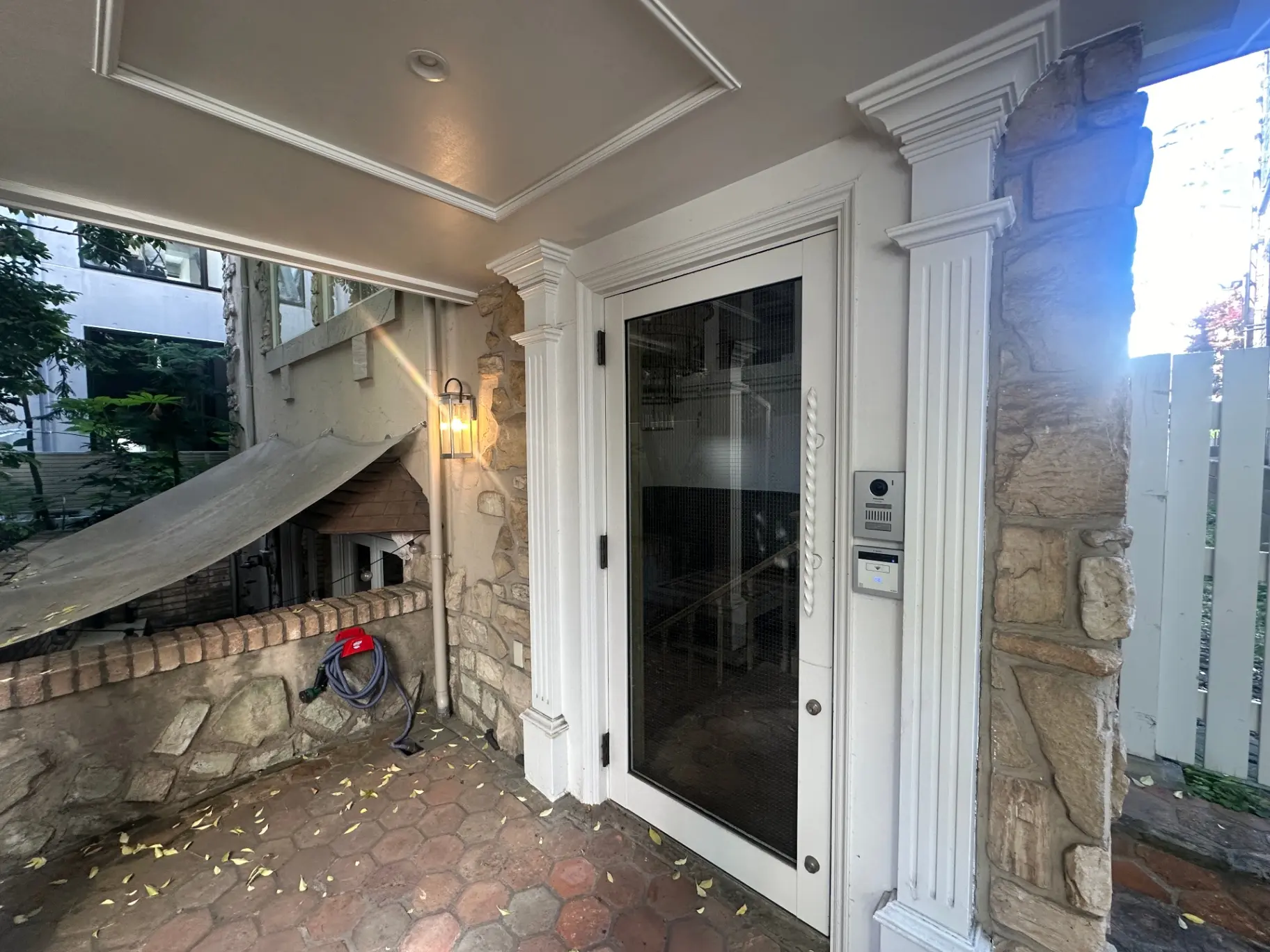 外観のエントランスとアプローチ、石造りの壁と照明設備が特徴的な家の入口