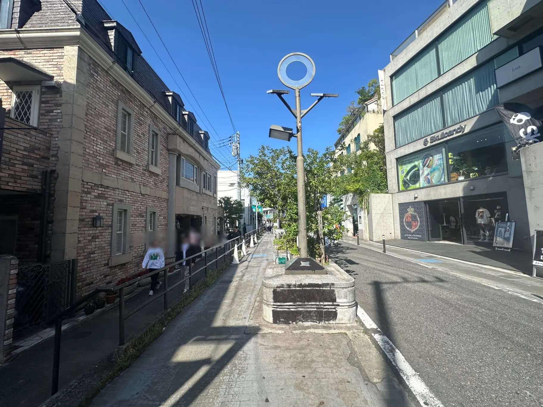 日差しが降り注ぐ都市の通り、青空と建物、街路灯の風景