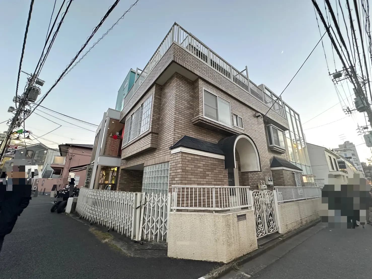 日没時の都市風景、レンガ造りの住宅、街路に沿った電線と歩行者