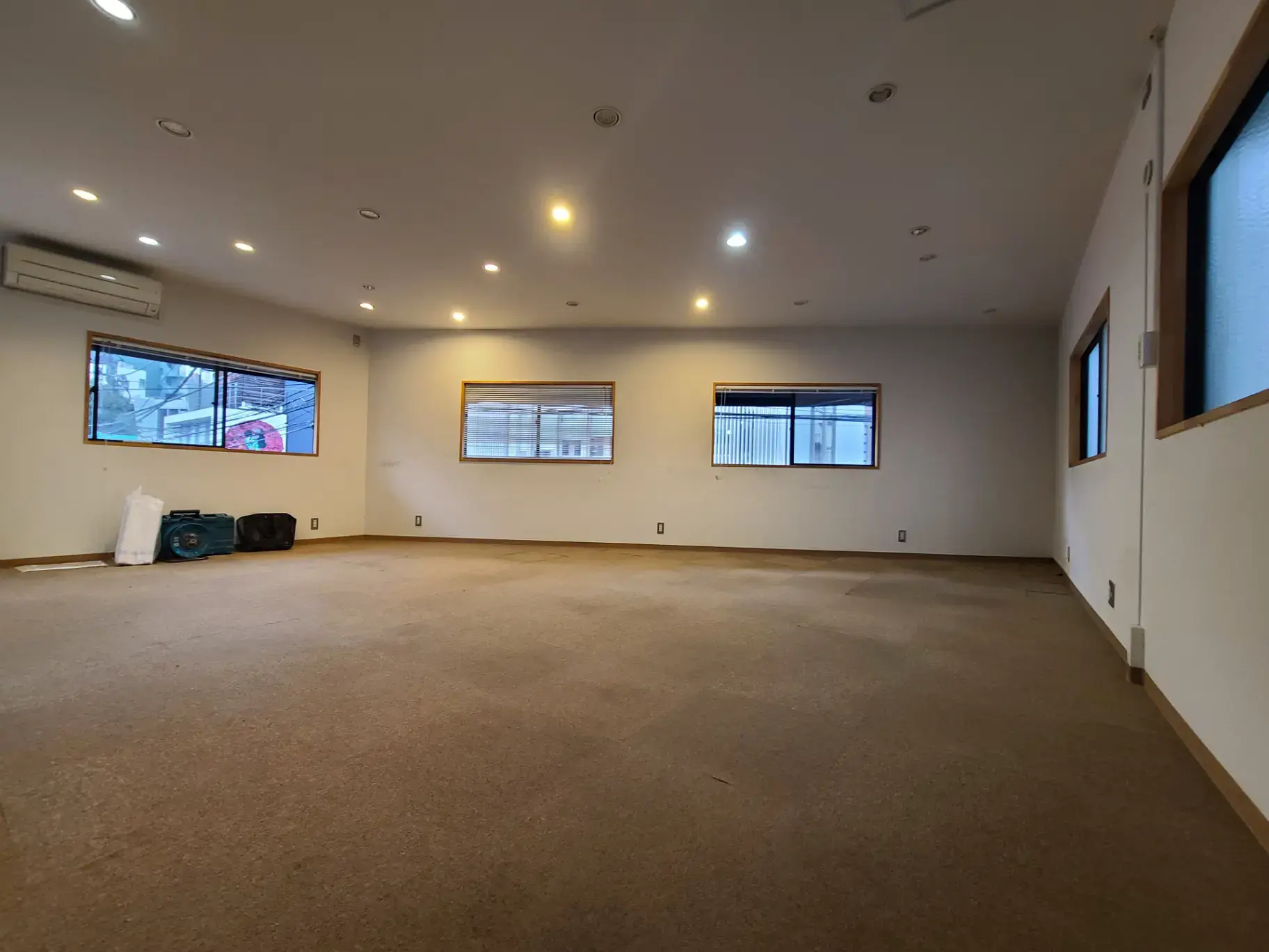 空のオフィススペースの内装、天井照明と複数の窓がある広々とした部屋