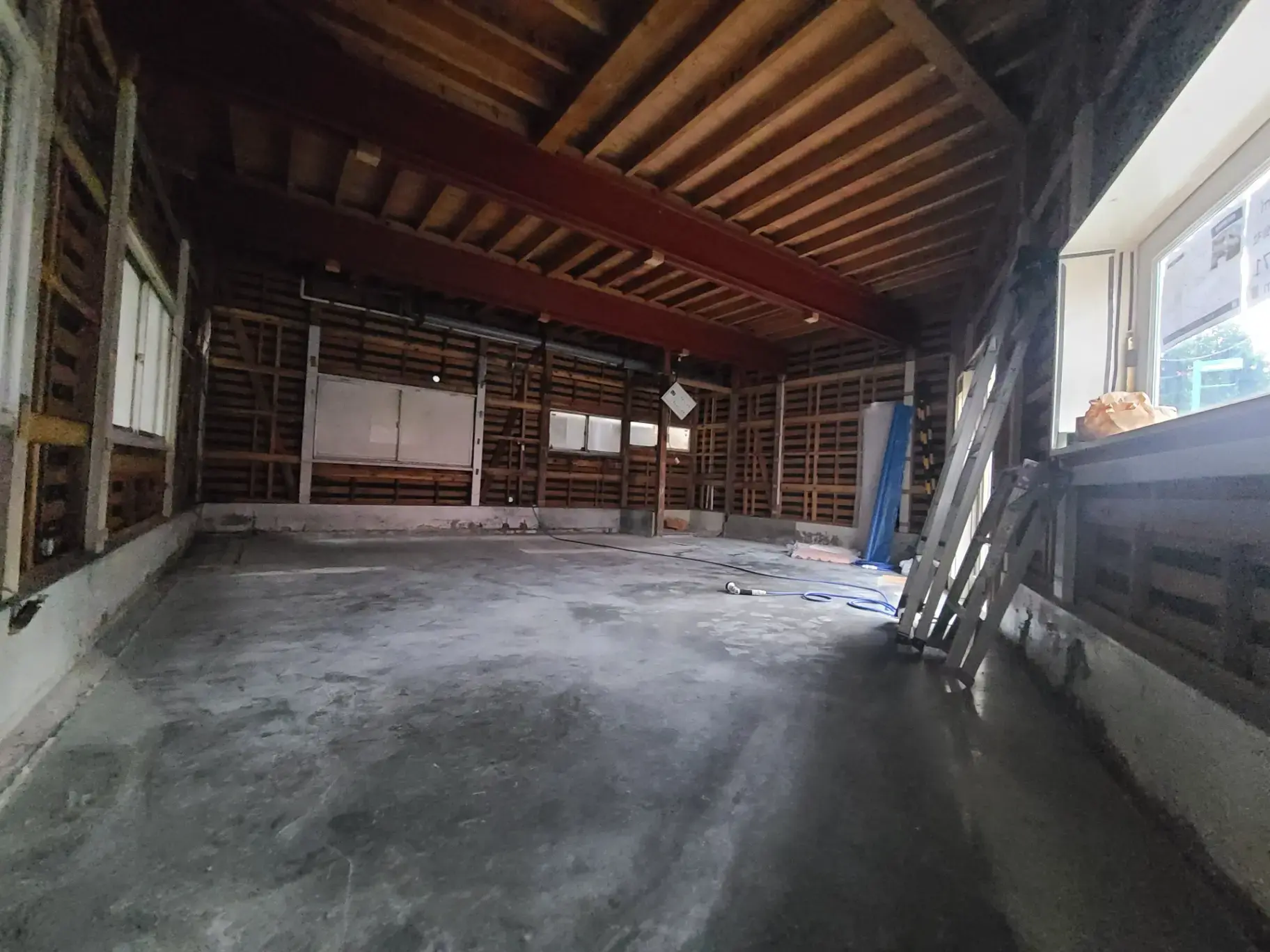 木造の天井と柱が特徴的な広々とした空の倉庫内部の画像