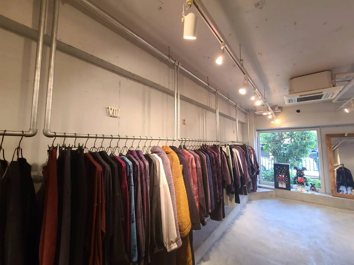 オシャレな洋服が並ぶセレクトショップ、コンクリートの壁と明るい照明の店内