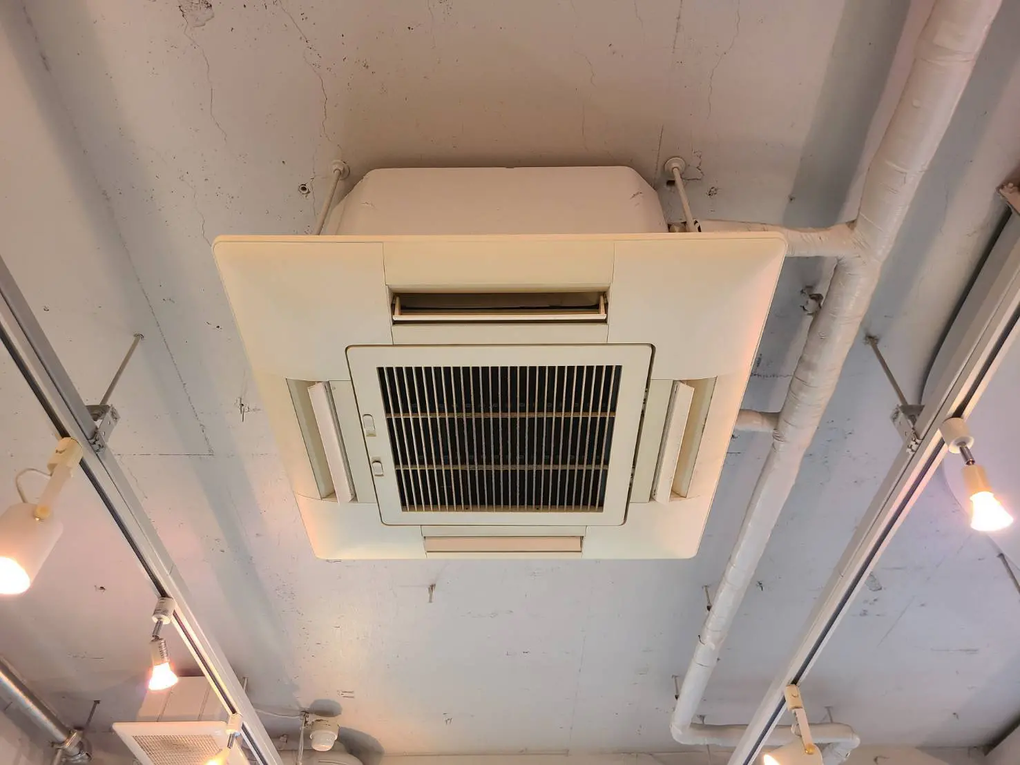 天井に設置された産業用エアコン、配管が見えるロフトスタイルのインテリア