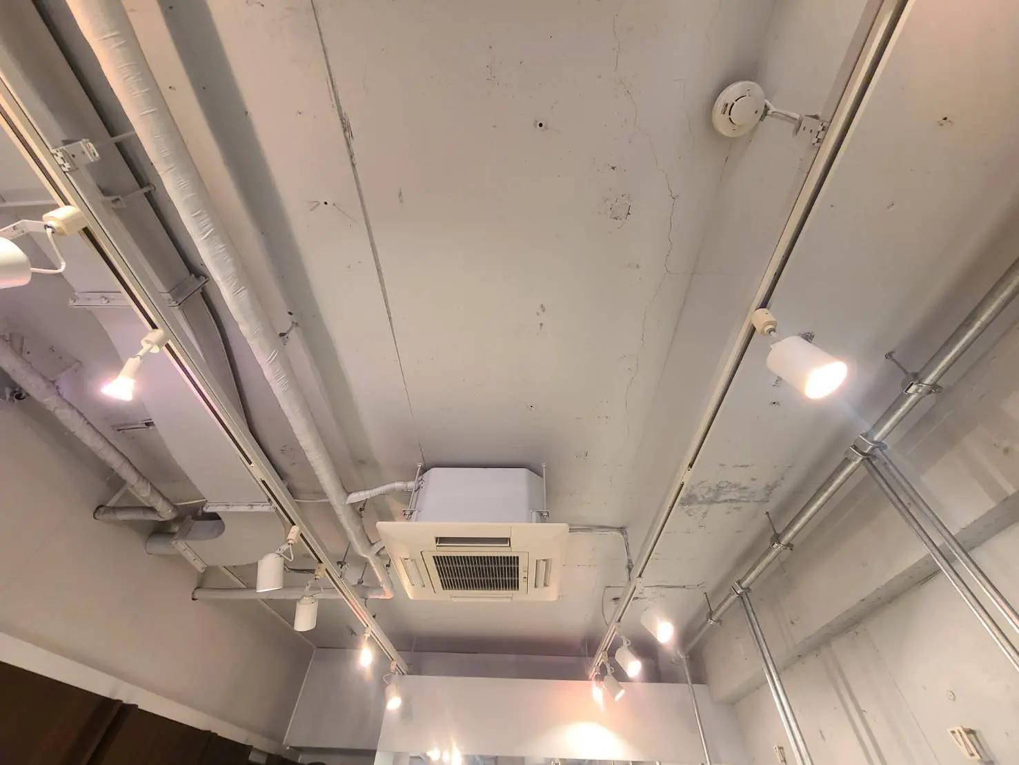 インダストリアルスタイルの内装、露出した配管とエアコンダクト、スポットライティングのある天井