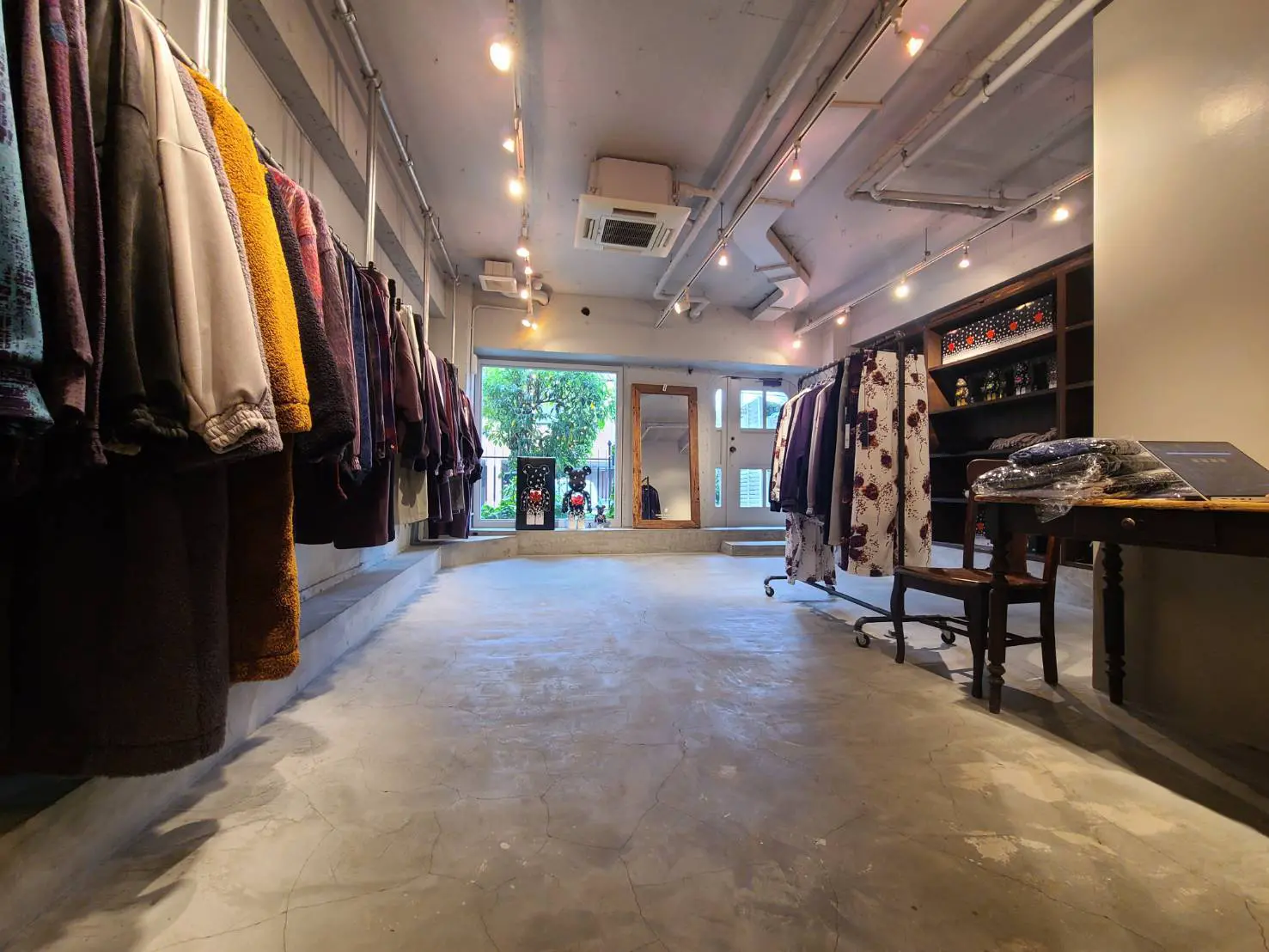 オシャレなアパレルショップの内装、壁にかけられた様々な色の服、スタイリッシュな照明と広々としたフロア