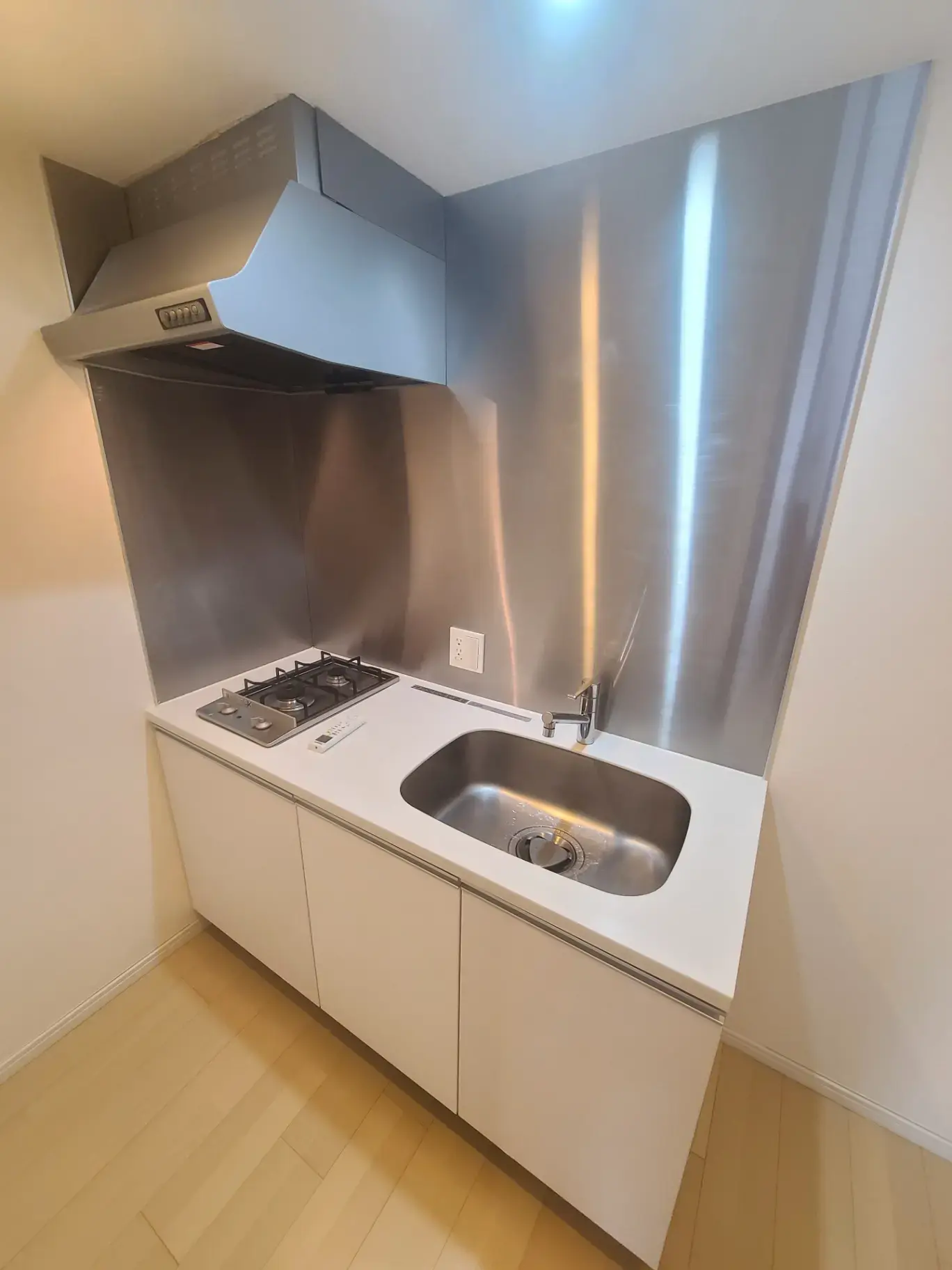 ステンレス製バックスプラッシュが特徴のコンパクトなキッチン