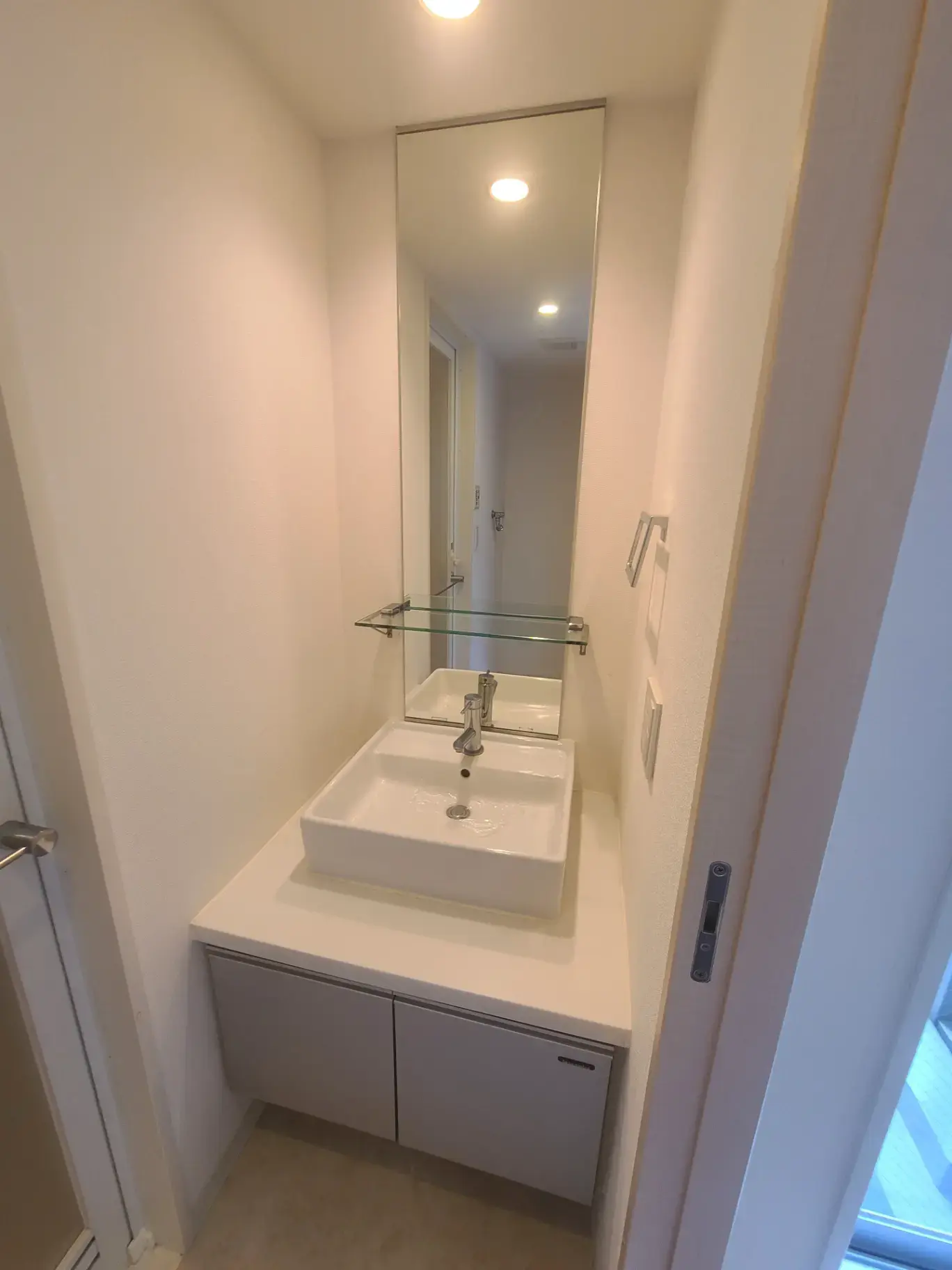 清潔感のある手洗い場所、壁面ミラーと収納キャビネット付き