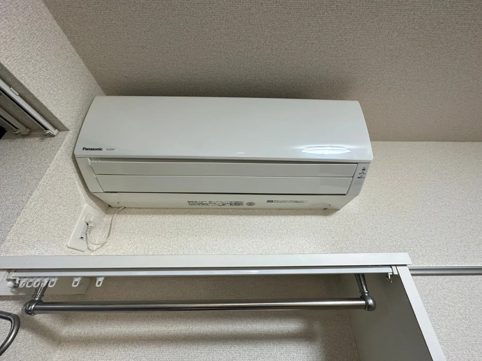 エアコンが設置されている室内の壁とハンガーラック