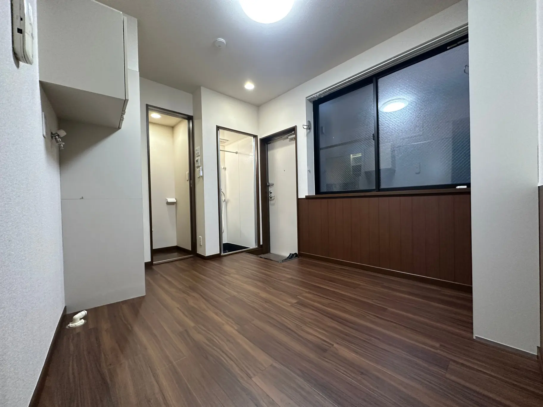 木目調フローリングが特徴的な明るい空間、ガラス戸の付いたバルコニー付き