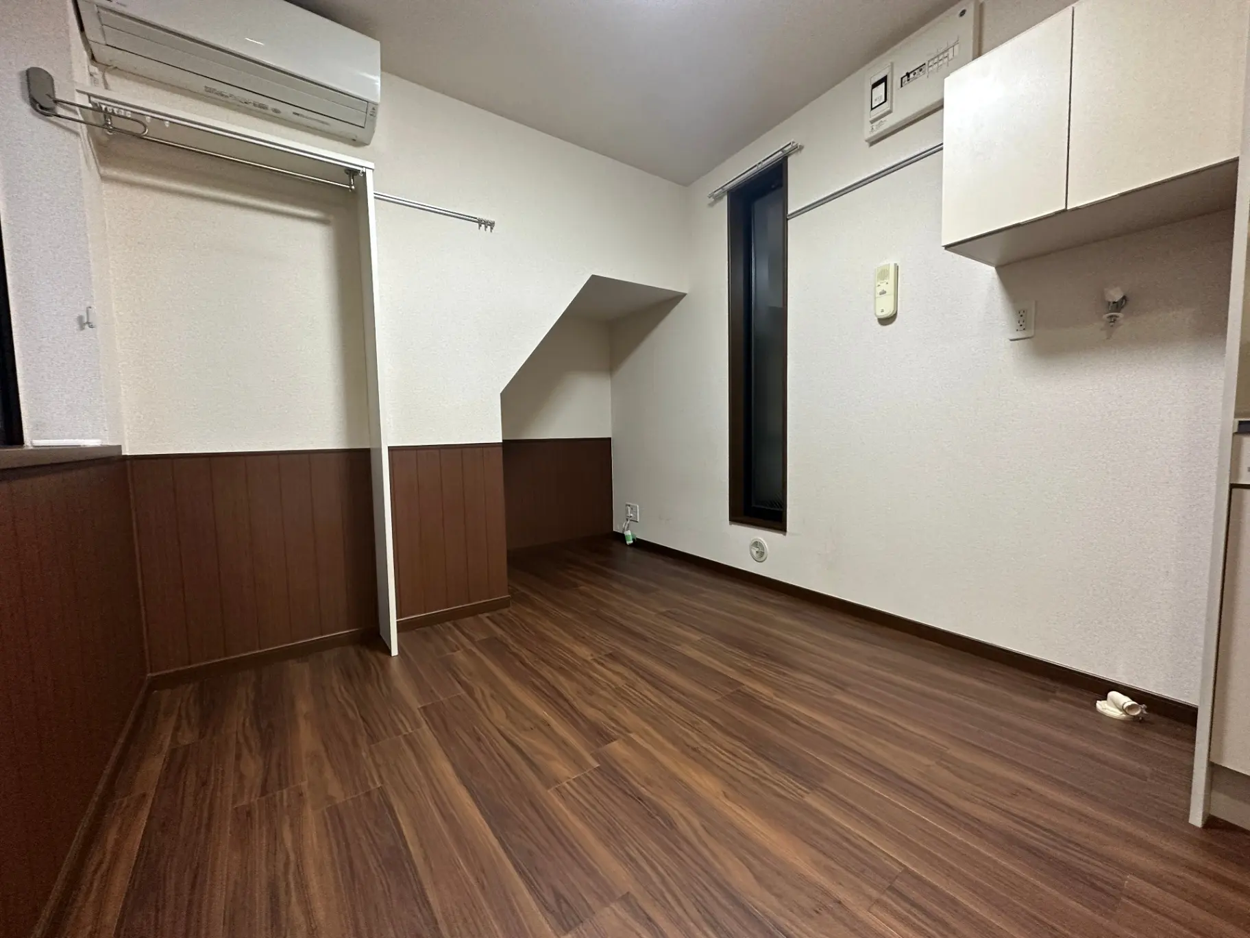 木目調のフローリングが印象的なシンプルな部屋、エアコンとクローゼット付き