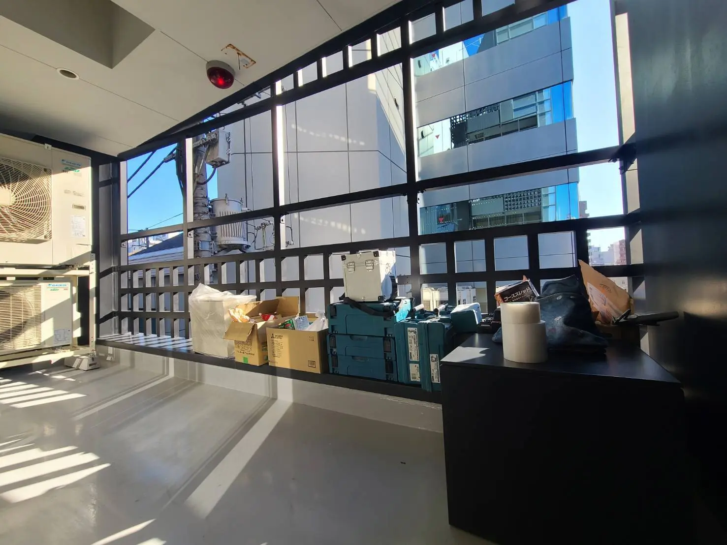 オフィスの窓辺に設置された作業スペース、都市のビル群を背景に日差しが差し込む室内環境