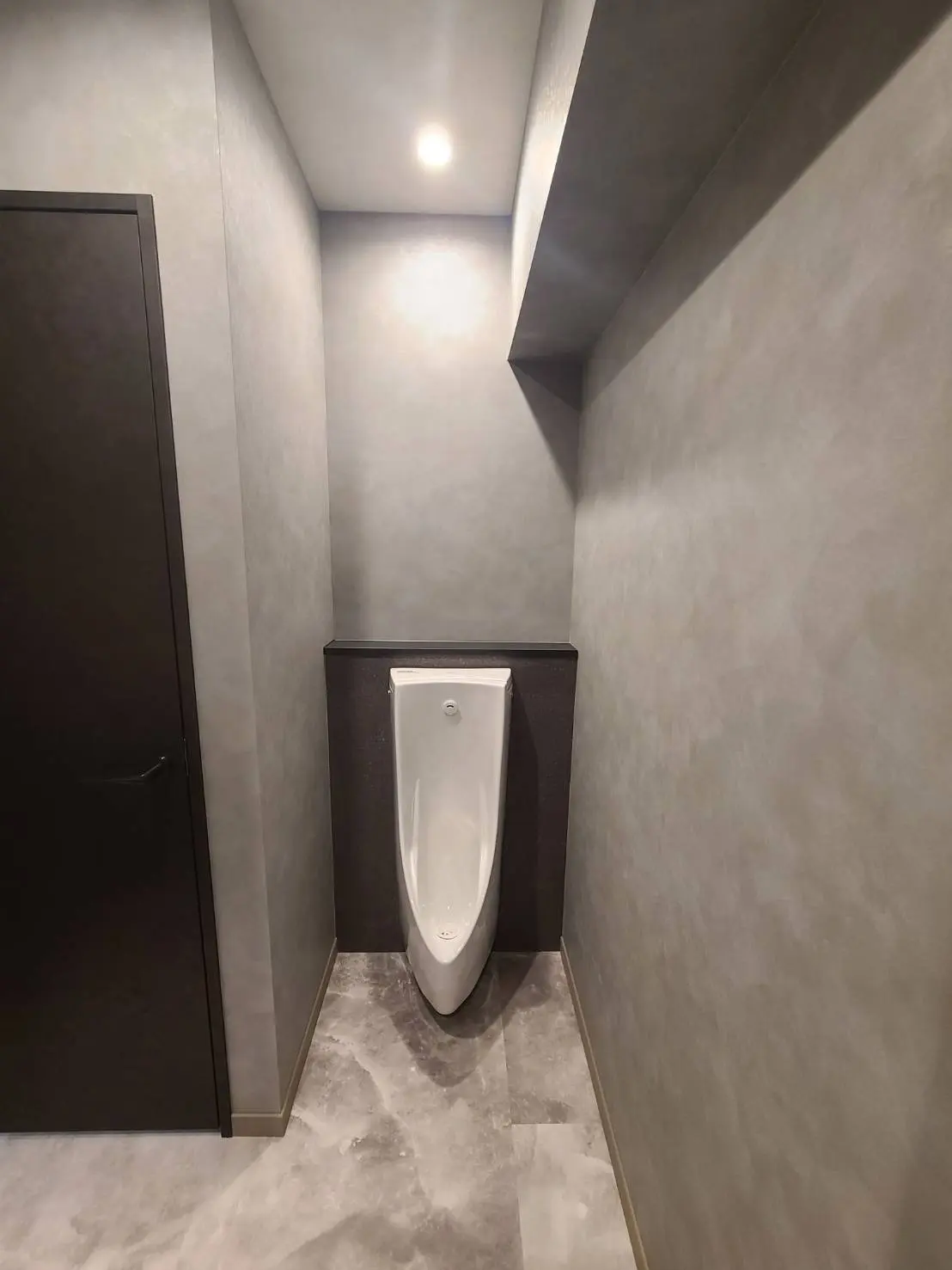 グレートーンの洗練されたデザインの公共トイレ、照明と大理石調のフロア