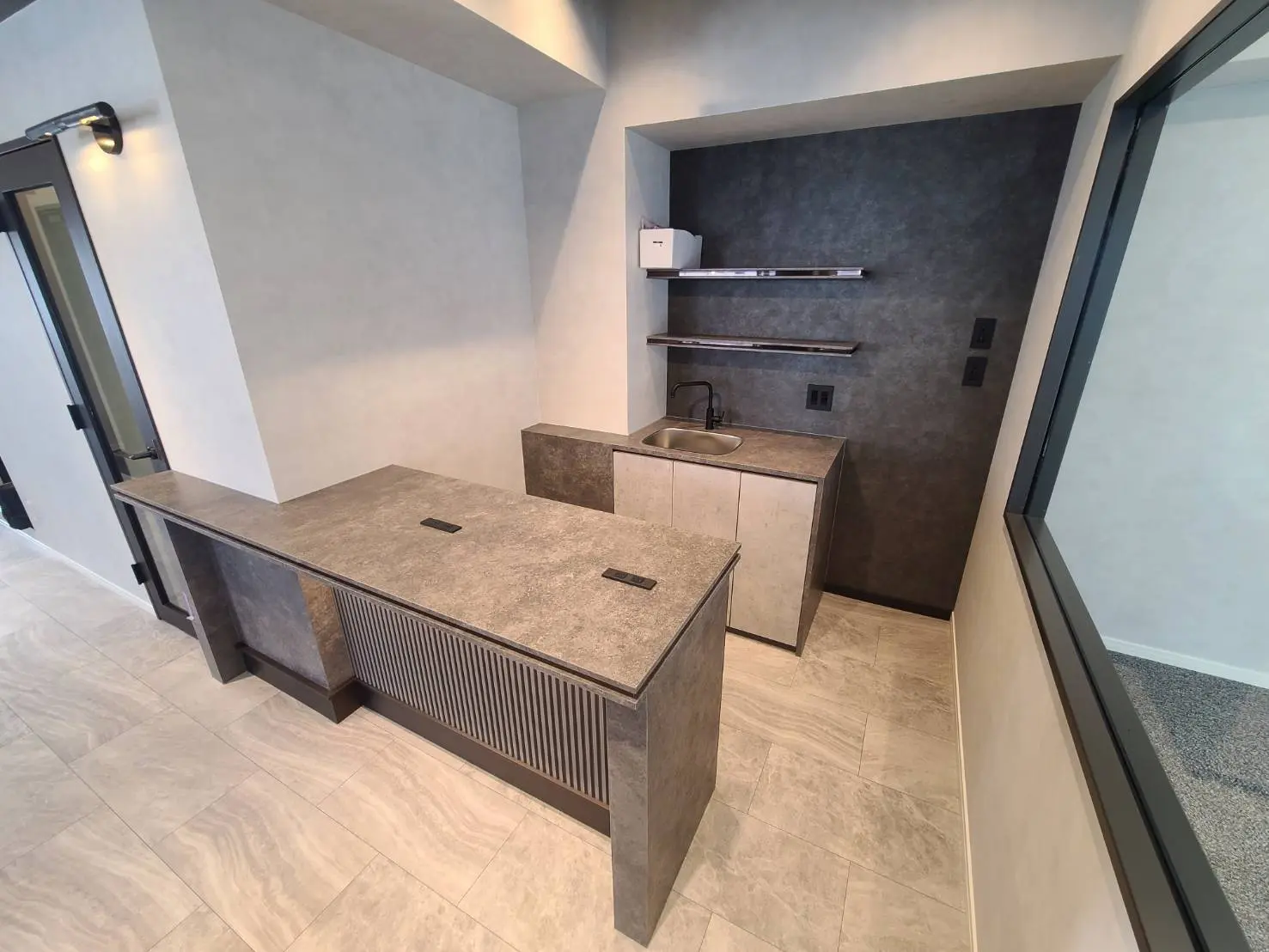 モダンなキッチンカウンター、シンプルなデザインの流し台と天然石仕上げ、床はタイル張り