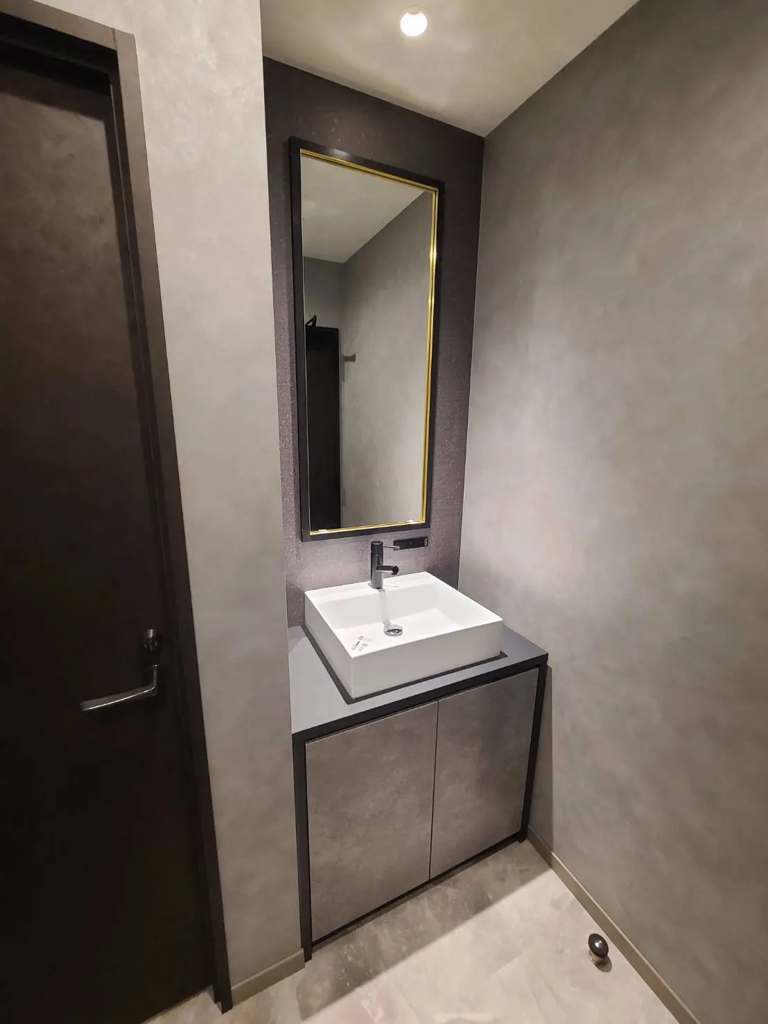 モダンな洗面台と鏡が特徴の洗面所、グレーの壁とタイル、シンプルでスタイリッシュなデザイン