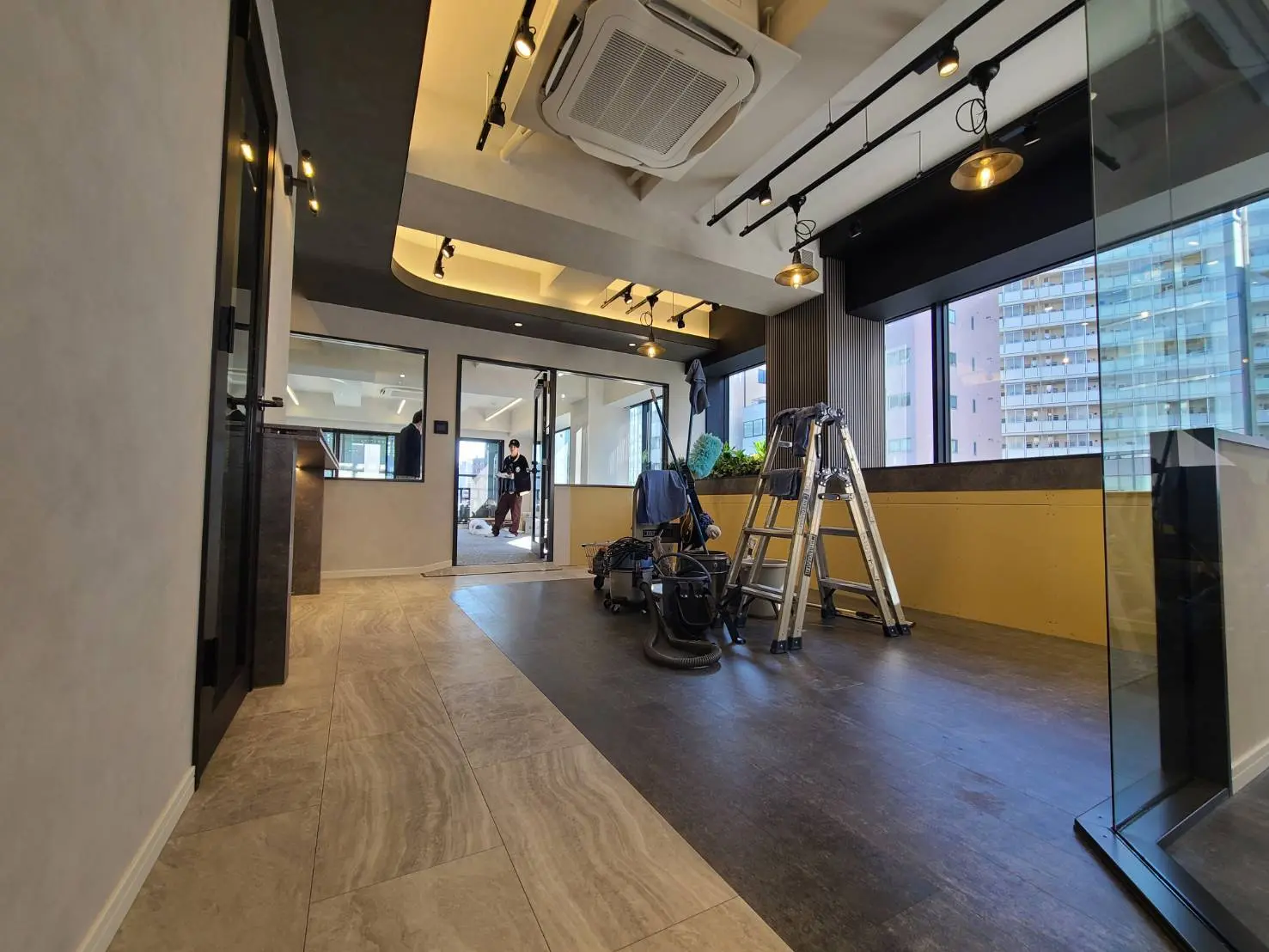 モダンオフィスのリノベーション中の内装、明るい照明とクリーンなデザイン、作業用梯子と掃除機が置かれている