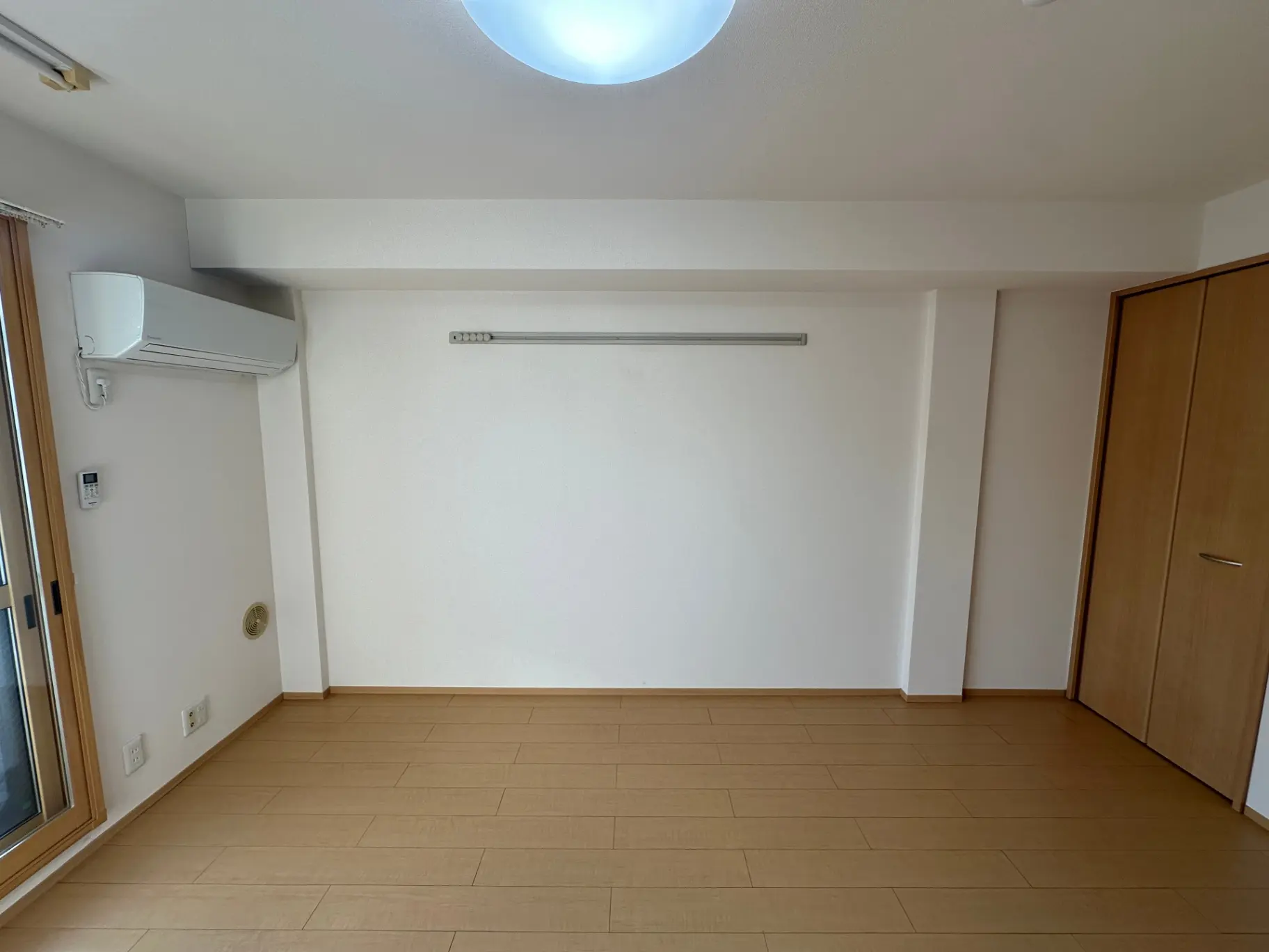 空白のリビングルーム、エアコンと収納クローゼットが設置されたシンプルなインテリアデザイン