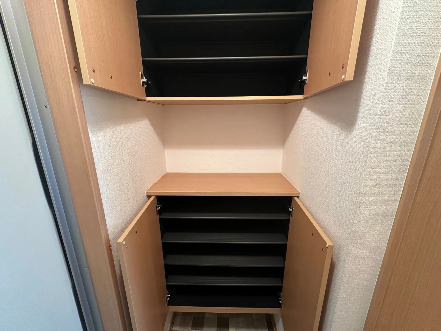 開いた状態の木製シューズボックス、黒い棚と茶色の扉、玄関収納のインテリア