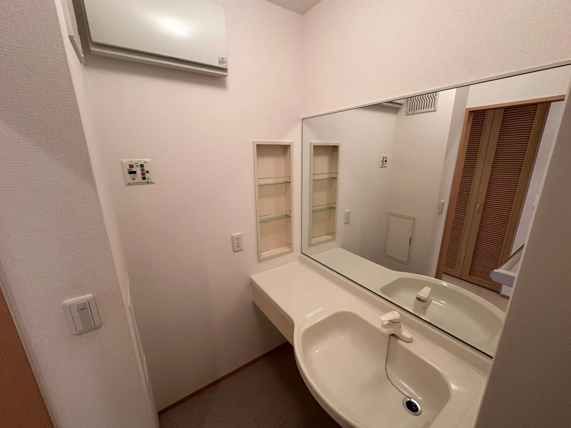 清潔感のあるシンプルな洗面所、大きな鏡と収納スペース付き、白い壁とベージュの洗面台