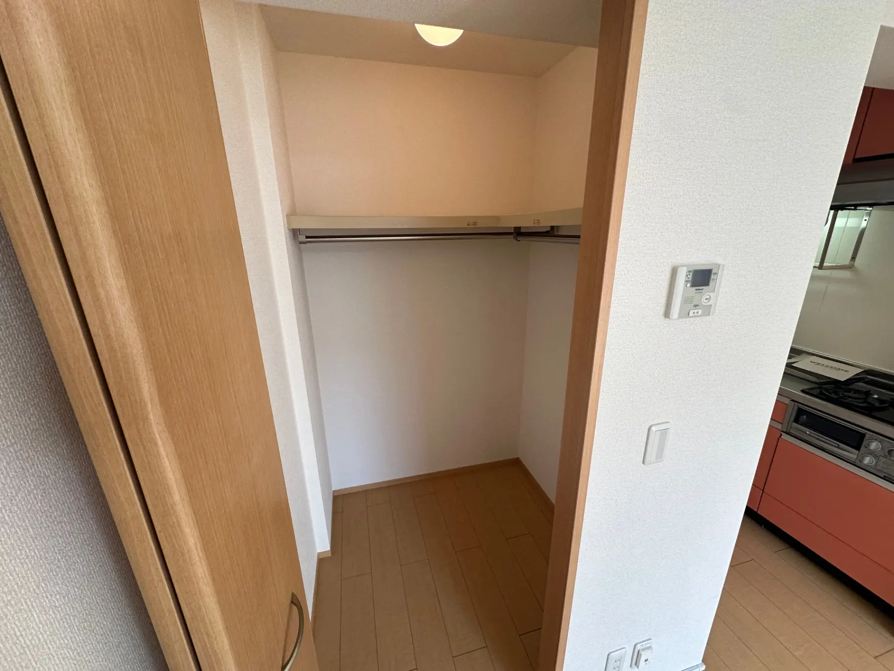 コンパクトなキッチン付きのワンルームマンション、シンプルなデザインのエントランスホール、明るい照明