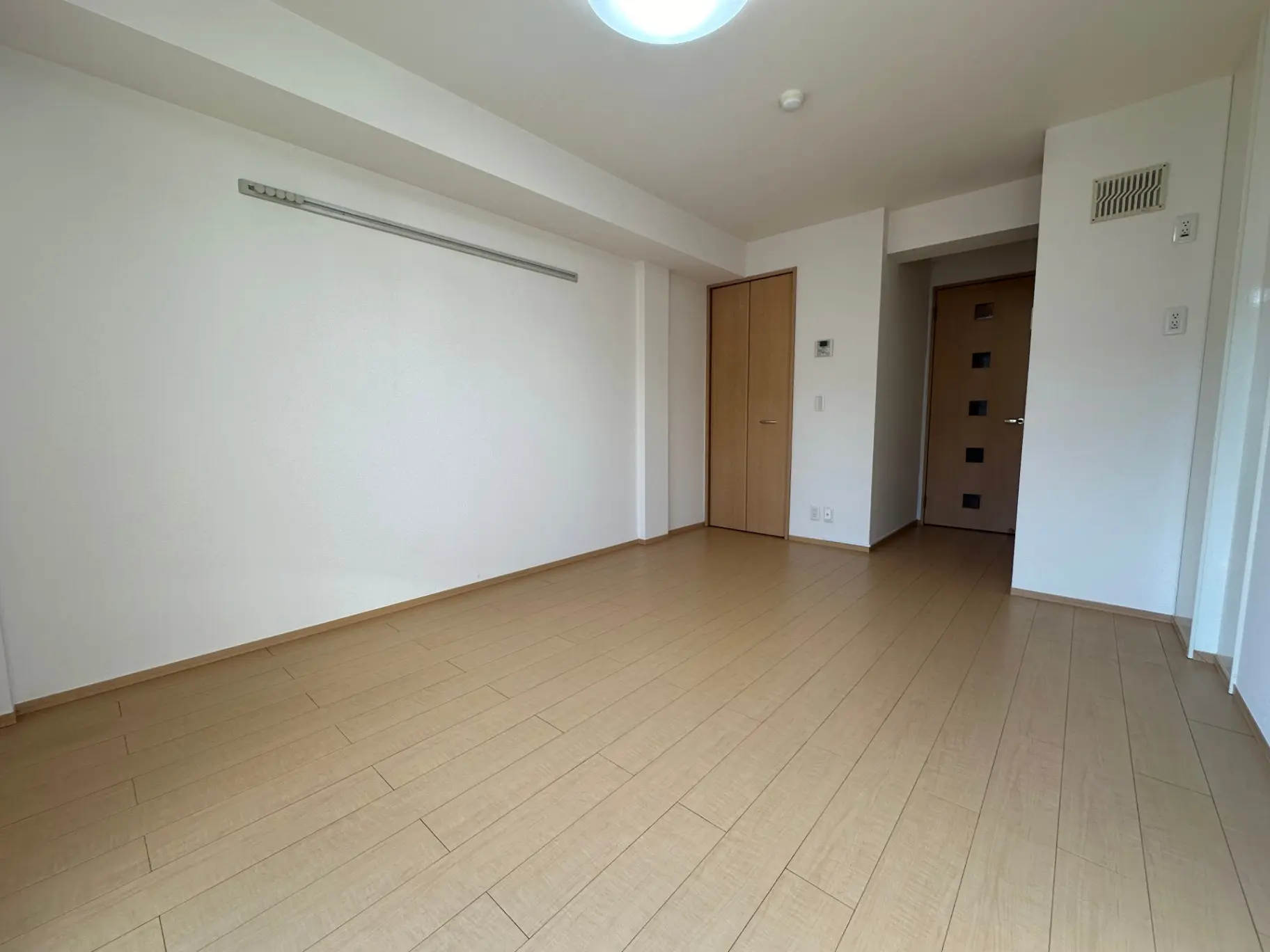 シンプルで清潔感のある空間、木目のフローリング、白い壁、光が差し込む明るい部屋のインテリア