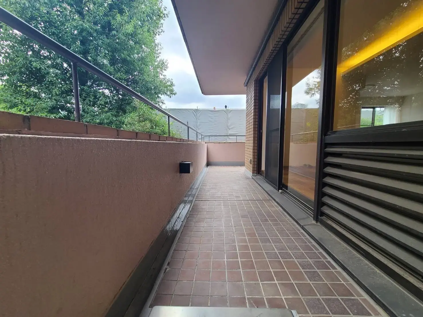 都会的なアパートの広々としたバルコニー、タイル張りの床、ガラス窓と手すりがある外観デザイン