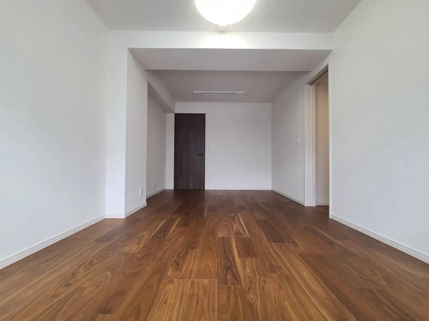 シンプルなデザインの空の部屋、茶色の木製フローリングと白い壁、照明付きの天井