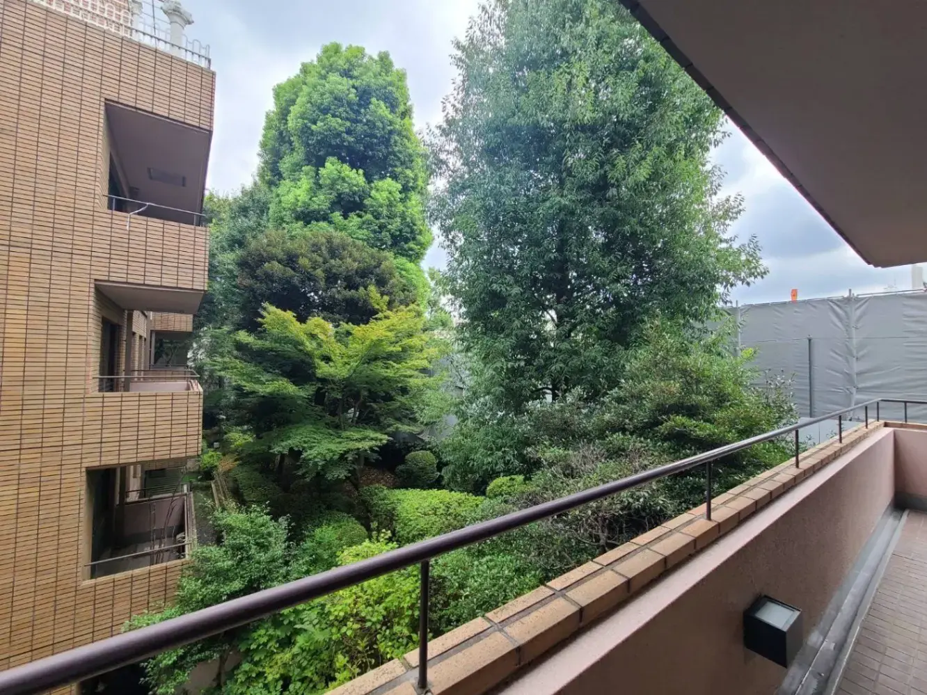 ベランダから見る都市の緑豊かな風景、周囲に建物が見える静かな住宅街