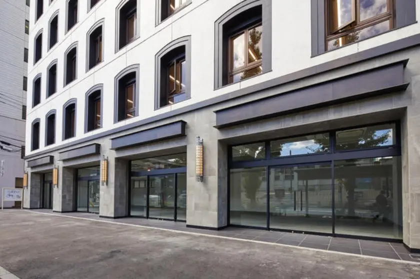 - モダンな外観の商業ビル、アーチ型の窓とシンメトリックなデザイン、両脇にある明るい照明付きのエントランス