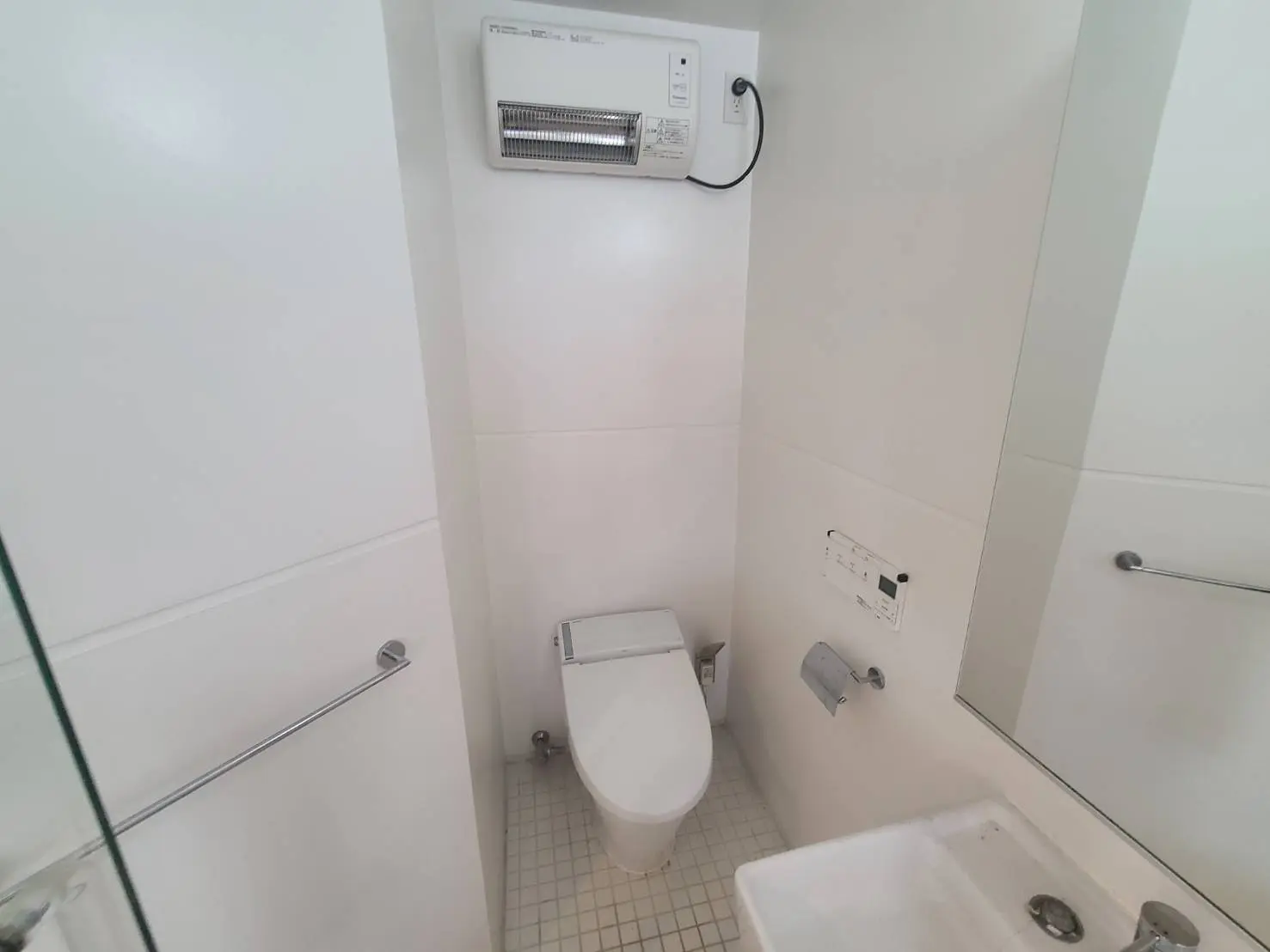 - クリーンでモダンなトイレの内部、白い壁と洗練された便座、洗面台、明るい照明のある空間