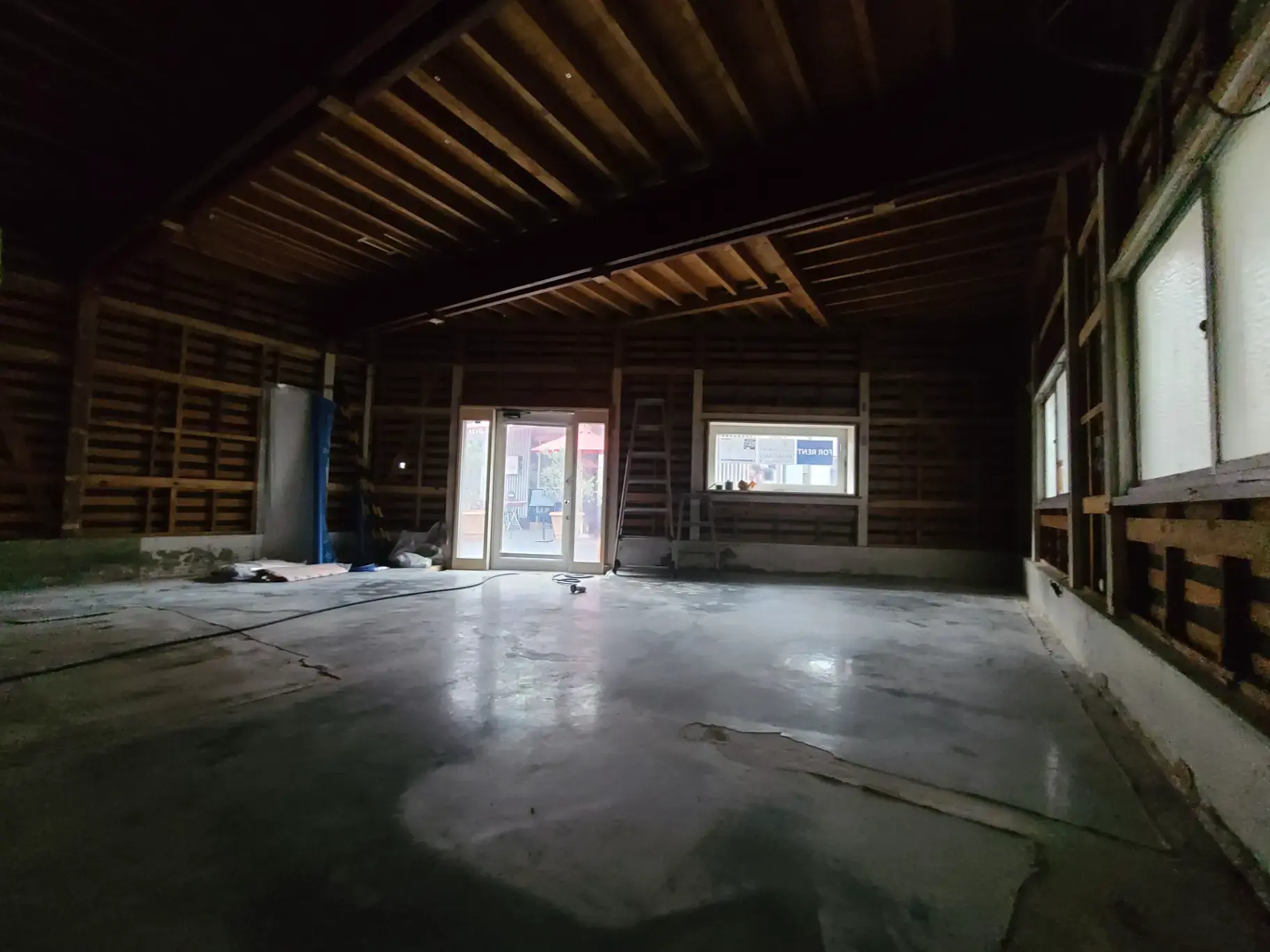 Alt属性:"夜間に照明された古い木造建築の室内空間、開いているガラス扉から外の光が差し込む"