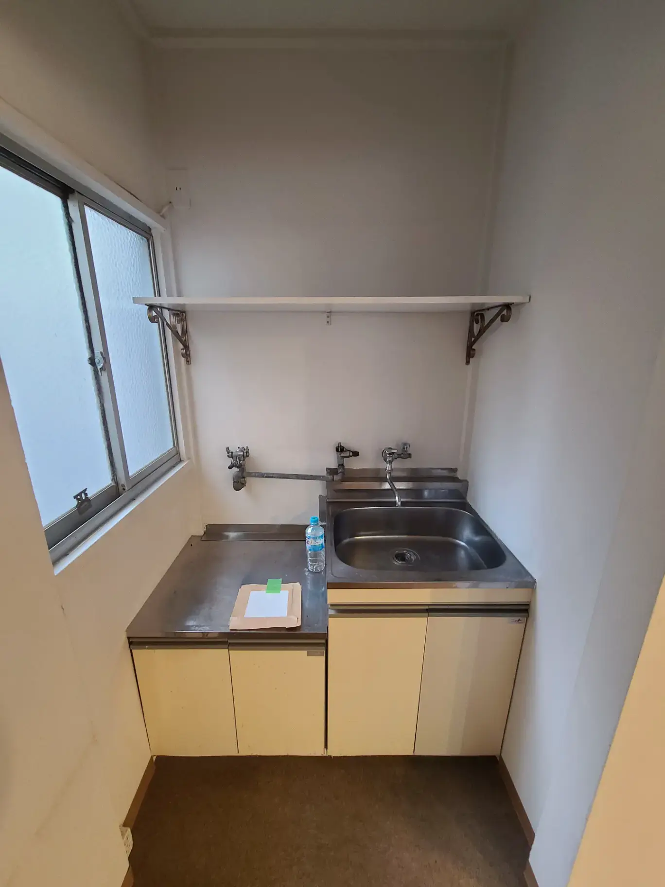 シンプルなキッチンのインテリア、ステンレス製シンクと棚、自然光の入る窓